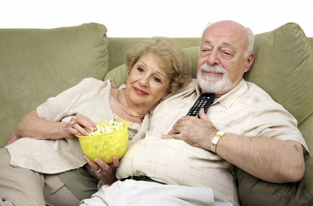 A senior couple relaxing and watching television together on the couch