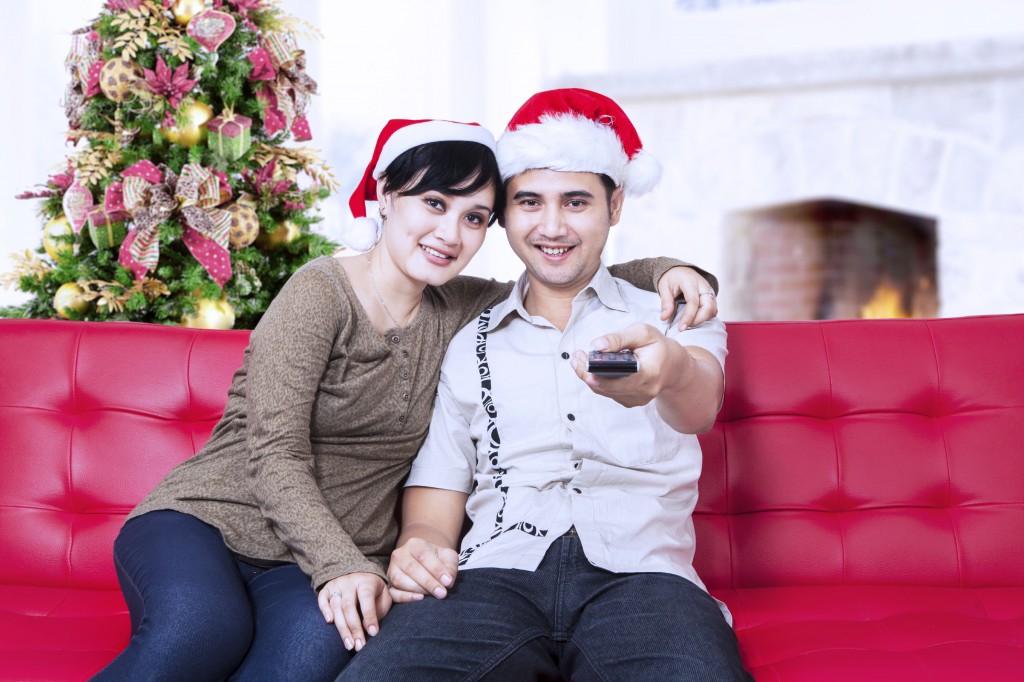 Happy christmas couple wearing santa's hats and holding a remote control
