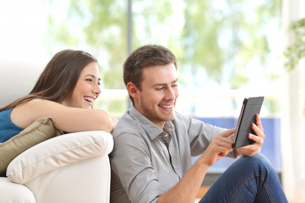 Cheerful couple using a tablet at home