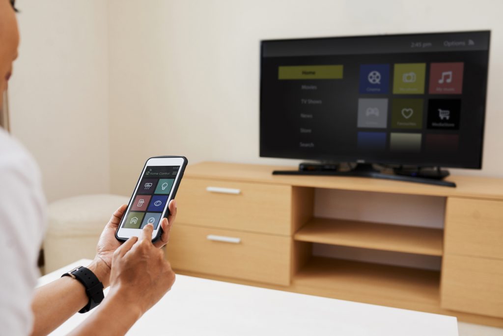 Woman screensharing from her smartphone to her smart tv.