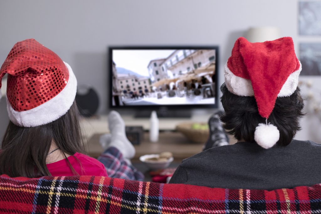 Couple wearing santa hats watching Christmas TV