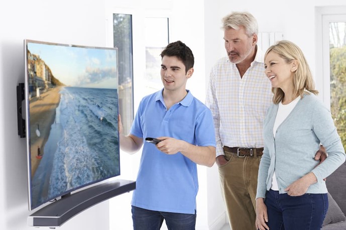 Couple being shown how to use their curved wall-mounted TV