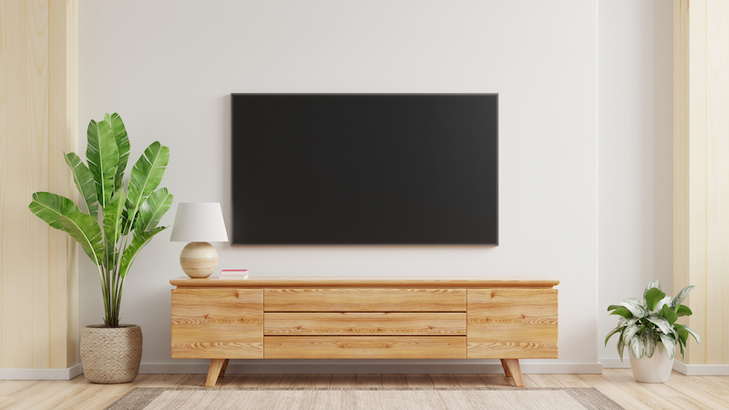 TV mounted on a wall with a TV stand and plants 