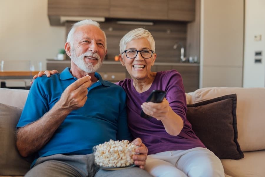 A person and person sitting on a couch and eating popcorn