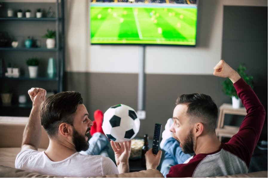 A group of men sitting on a couch watching a football game